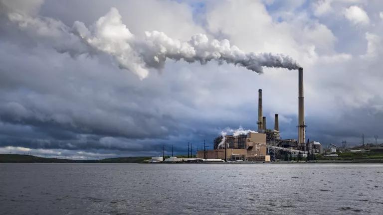Emissions rise from a stack on a power plant situated on the edge of a body of water