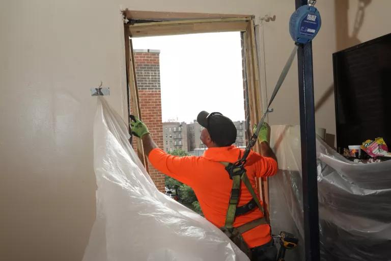 A construction worker handles a piece of lumber in a windowframe