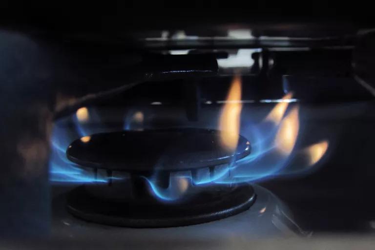 Blue and orange flames rise from a burner on a gas stove