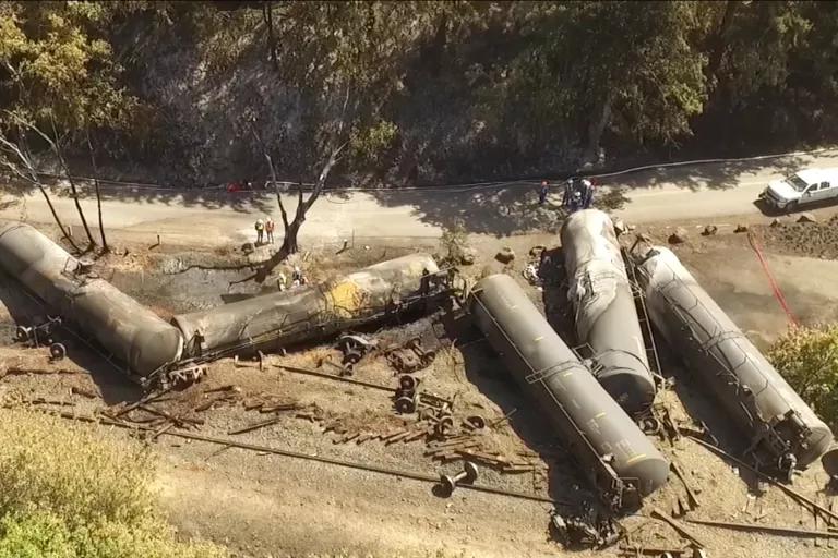 Crashed oil tanker train cars lie burned near railroad tracks