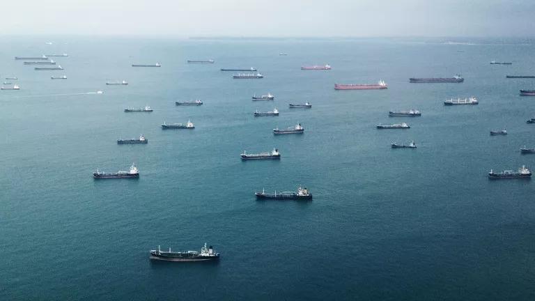 An aerial view of open water dotted with dozens of large vessels