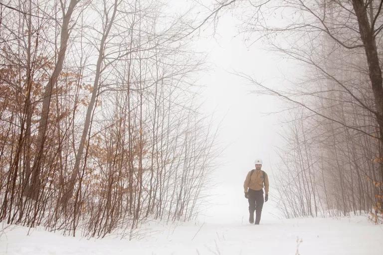 A man walks through a snowy wooded area