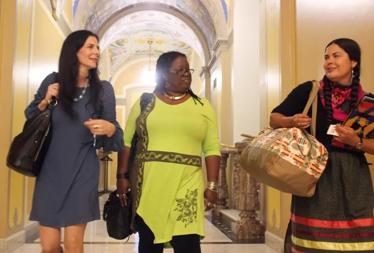 Three women walk inside a hallway of the U.S. Capitol building