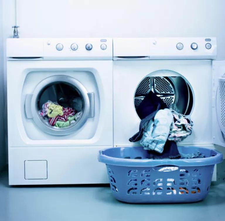A washer and dryer side-by-side with a laundry basket in front of the dryer