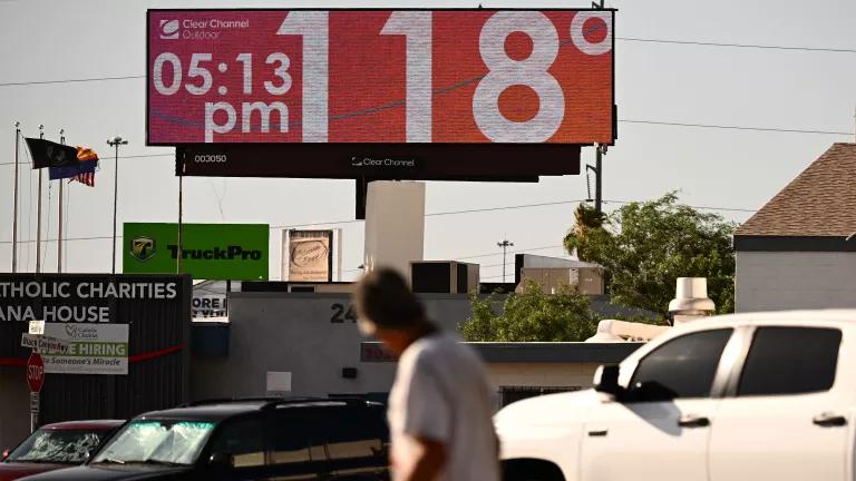 An adult looks up at a digital billboard, which shows the current temperature has reached 118 degrees Fahrenheit during a major heat wave in Phoenix.
