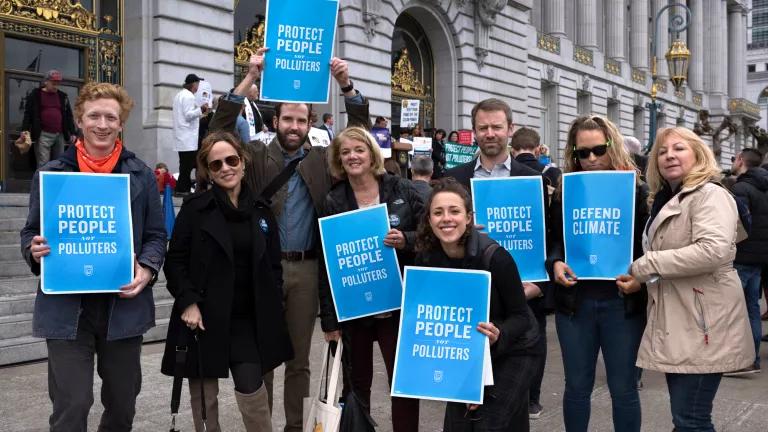 A group of NRDC staff holding protest signs that read "Protect people not polluters"