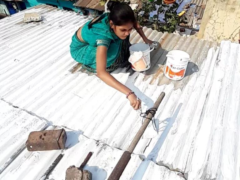 Ahmedabad slum resident Gudiyaben painting her rooftop with solar reflective paint