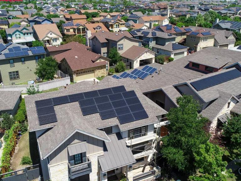 An aerial view of a residential neighborhood with solar panels on the roofs of many houses