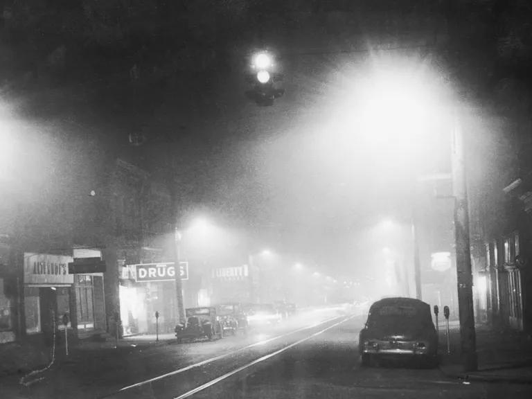 A black and white image of a darkened city street 