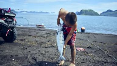 A boy holds a fish. 
