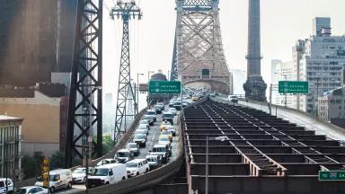 Two lanes of bumper-to-bumper car traffic on a city bridge