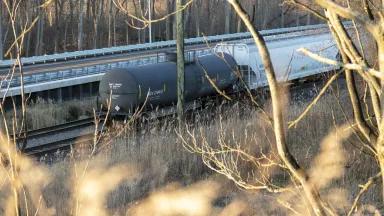 Tanker rail cars on train tracks in a wooded area