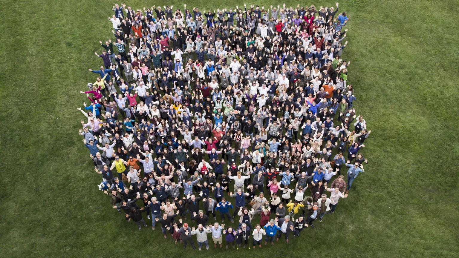 An aerial view of NRDC staffers standing together in the shape of a shield on green grass