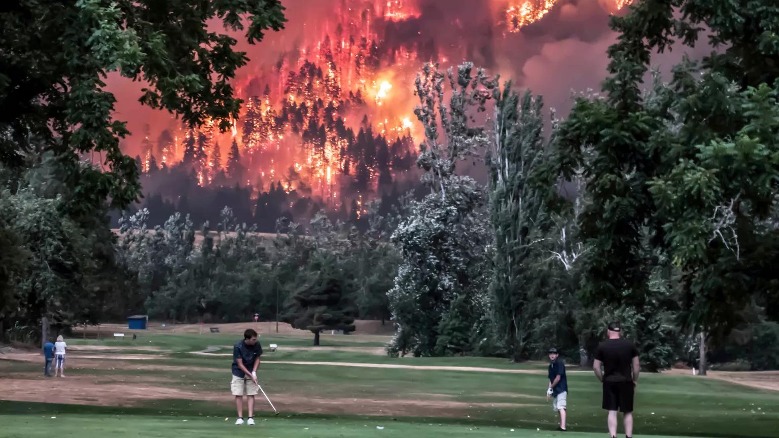Golfers play at the Beacon Rock Golf Course as flames from the Eagle Creek Fire blaze nearby in North Bonneville, Washington, on September 4, 2017.