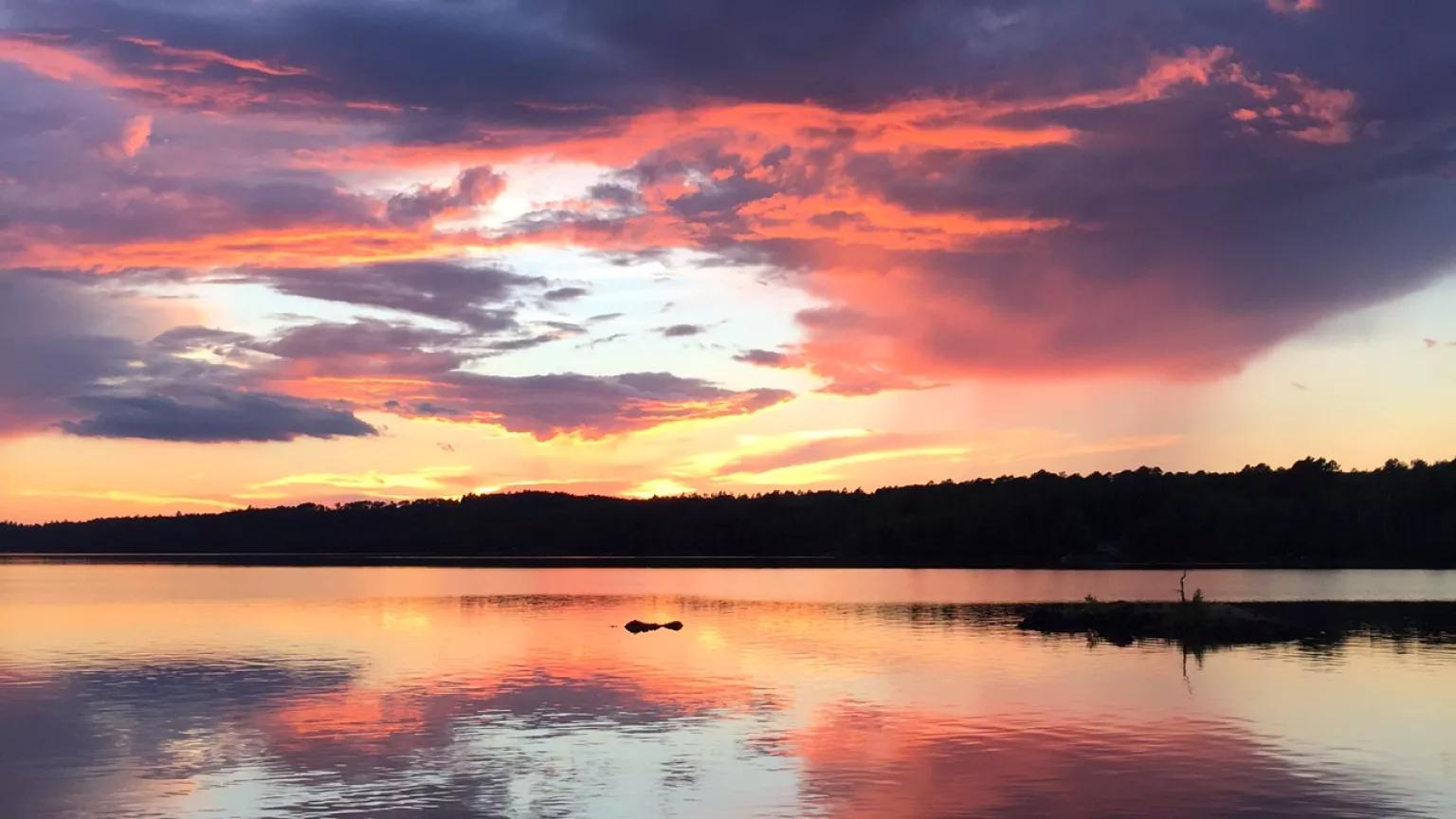 A scenic view of a lake under a sunset sky