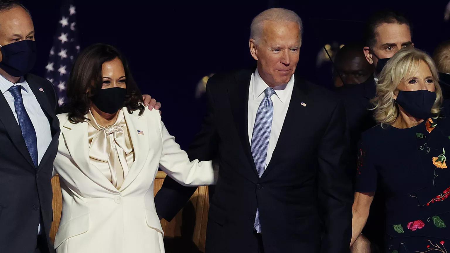 Doug Emhoff, Vice President Kamala Harris, President Joe Biden, and Jill Biden stand on a stage and wave