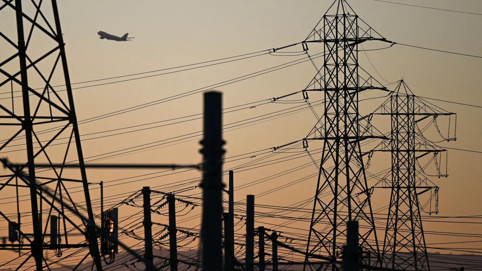 An airplane flies over electric power lines near Los Angeles International Airport