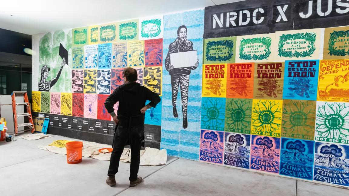 Artist Erik Ruin installing poster art at the NRDC exhibit during EXPO CHICAGO at Navy Pier in Chicago, Illinois, on April 10, 2022. NRDC and Justseeds Artists’ Cooperative showcased the work of over 30 artists in an outdoor mural installation with live screen-printing