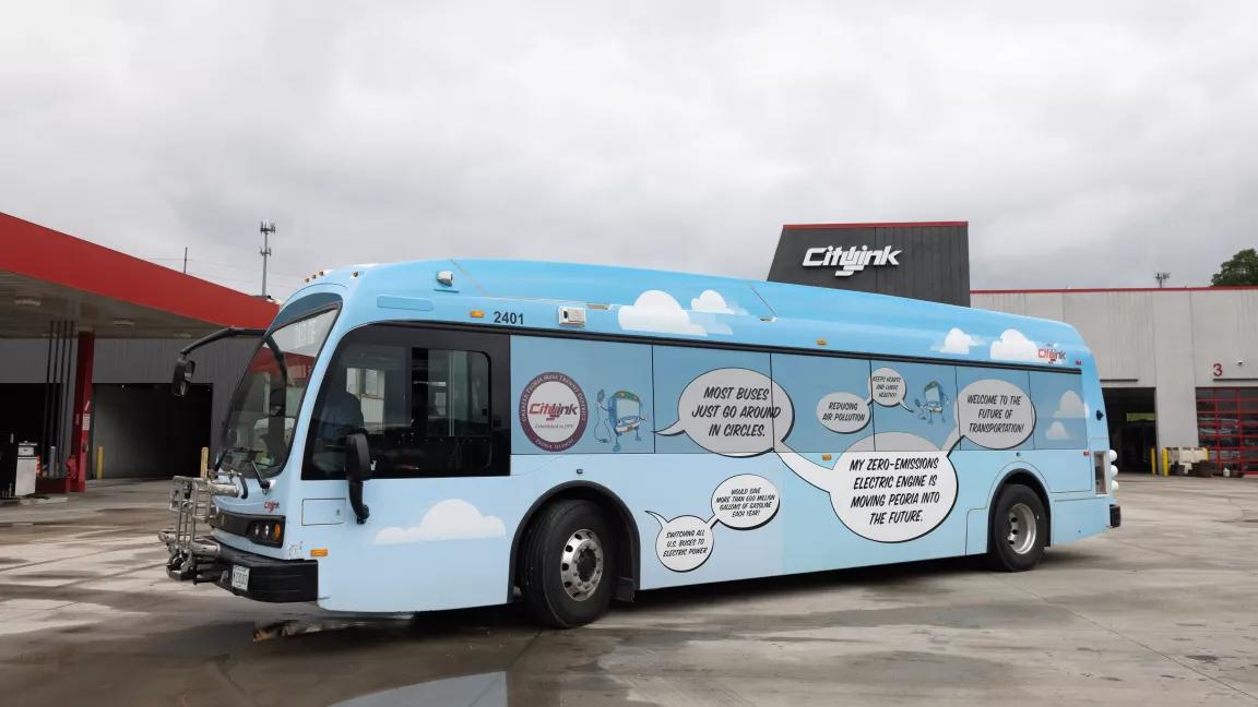 A light-blue bus painted with clouds and speech bubbles