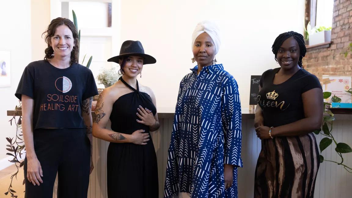 Four people standing next to each other, in front of a counter indoors