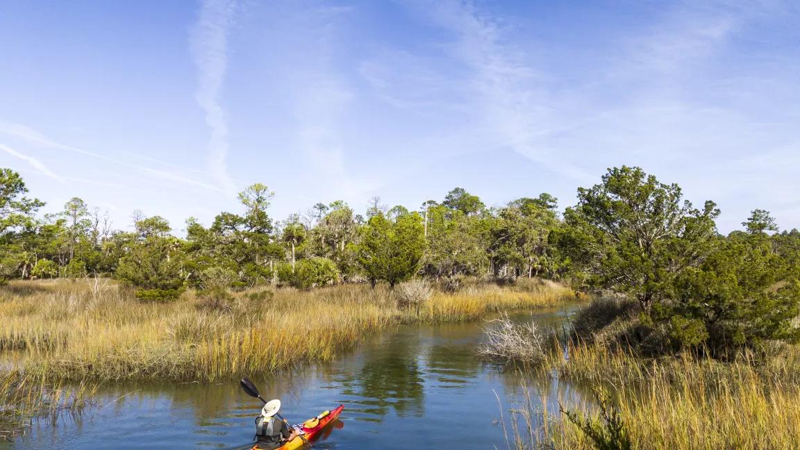A kayaker paddling through a waterway in Skidaway Island State Park, Georgia.