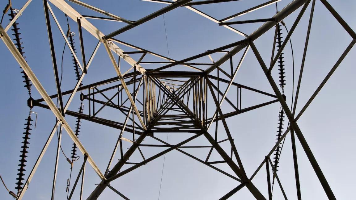 Person's ground up view of high voltage electric pylon tower