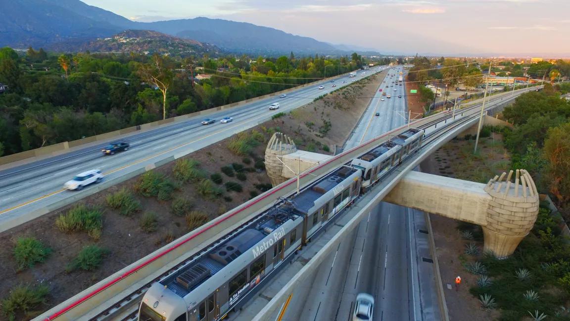 A Metro Gold Line train traveling over a bridge across the freeway