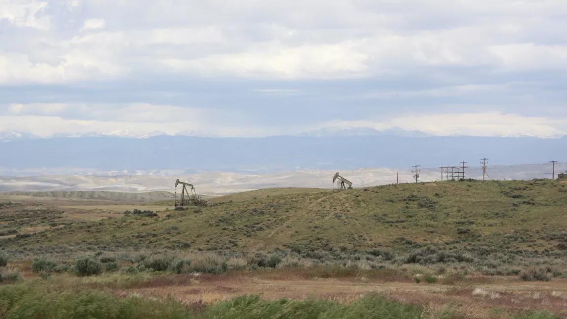 A picture containing grass, outdoor, sky, field, and pump jacks. 