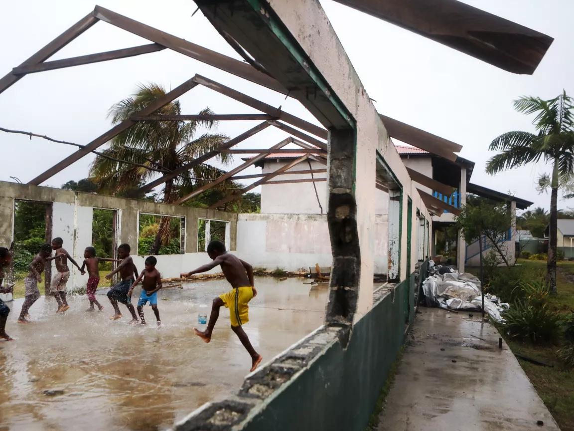 A view of children playing in a flooded building without a roof and windows after Cyclone Pam in Tanna, Vanatu 