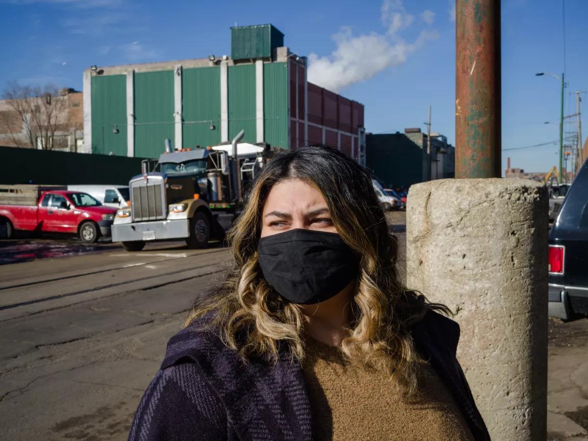 NRDC's Gina Ramirez standing in front of the General Iron car-shredding facility in Chicago, wearing a mask