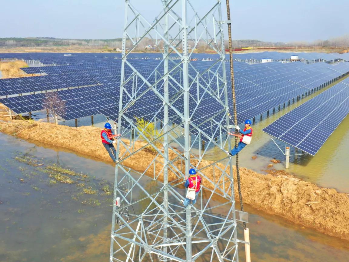 An aerial view of workers high up on a transmission tower for a tide-light complementary photovoltaic power station in China