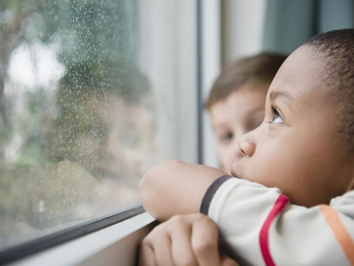 Children look out the window on a rainy day.