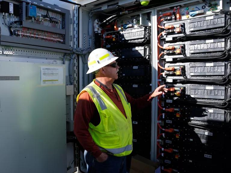 A construction manager checks on a battery storage pod.