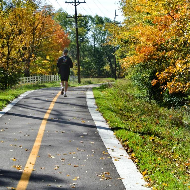A man jogs on a paved pathway