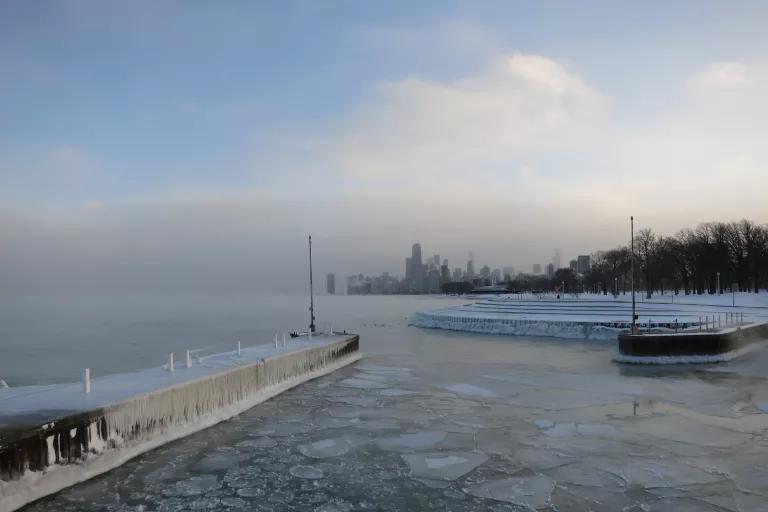 An icy lake with a city skyline in the distance