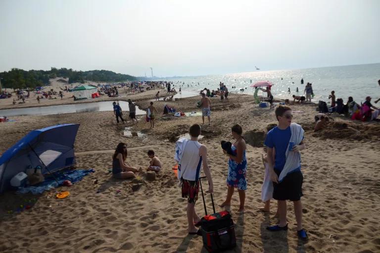 People sunbathe and stand on a sandy beach