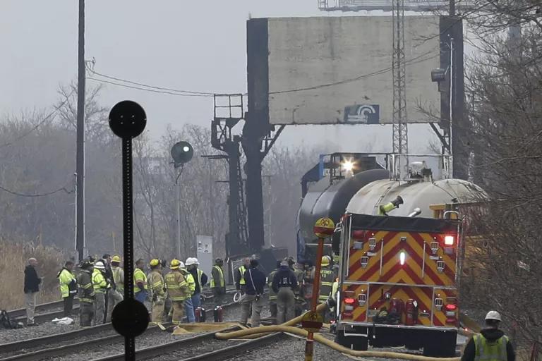 Emergency workers stand on train tracks next to derailed cars