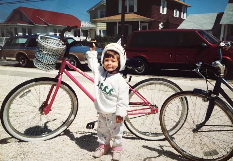 Photo of a toddler standing in front of bicycles at the beach.