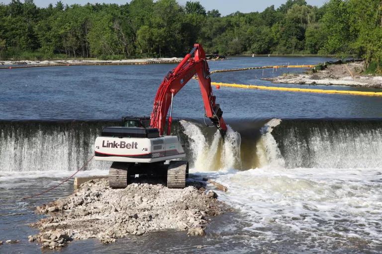 A large crane on a berm in the middle of a riverbed