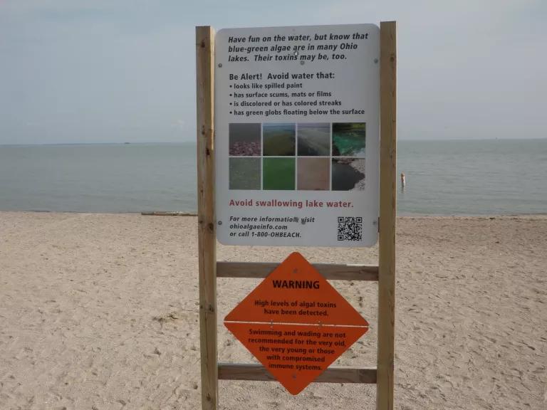 Sign on the shores of a lake, warning people to watch out for harmful algae