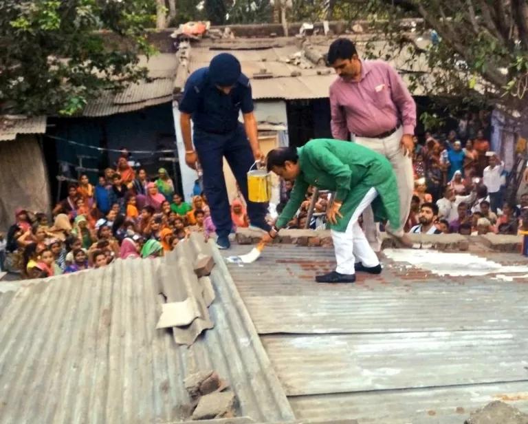 Ahmedabad Mayor Gautam Shah (center) painting a 'cool roof' with white paint in Ahmedabad, India, in April, 2018.