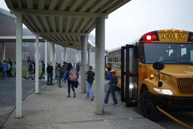 Students exiting a school bus in front of a school building
