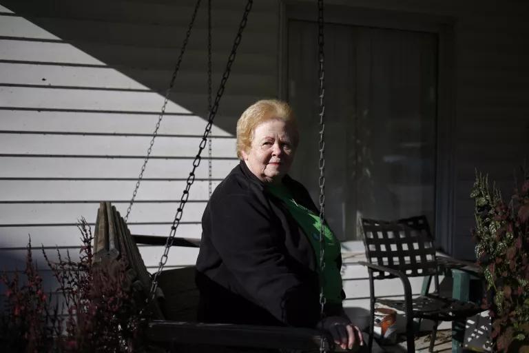 A woman sit on a swing on a covered porch