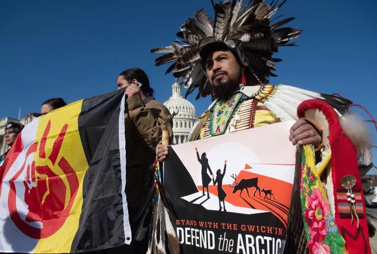 Protesters in front of the U.S. Capitol building carry flags and a sign that reads in part "Defend the Arctic"