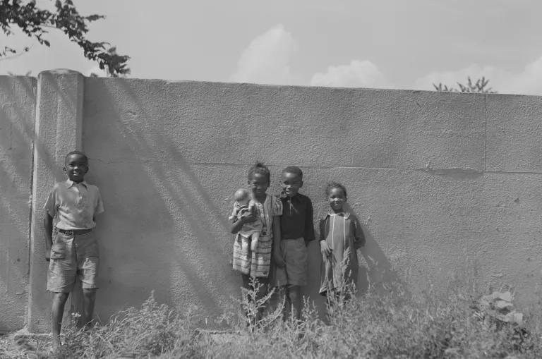 Four children standing in front of a concrete wall