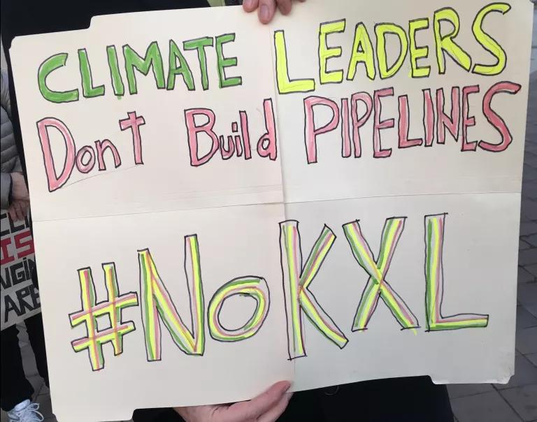 A hand-drawn poster reads "Climate Leaders Don't Build Pipelines; #NoKXL"