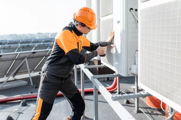 Technician installing a rooftop heat pump system