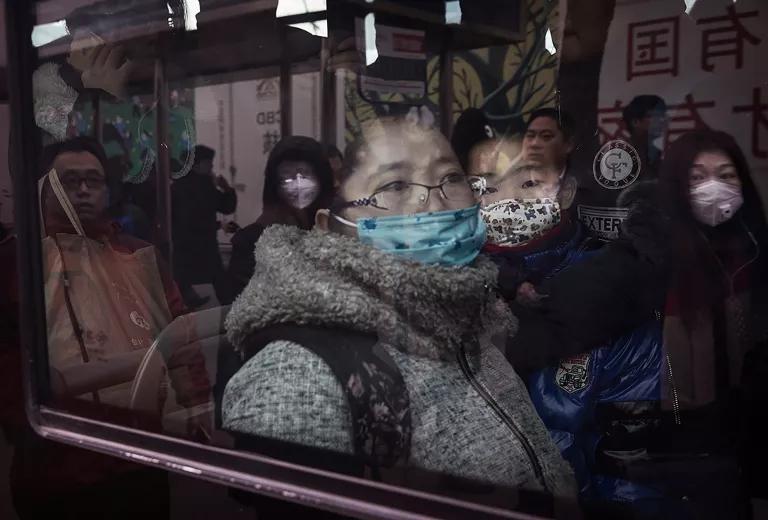 A woman and young child wearing face masks look through a window