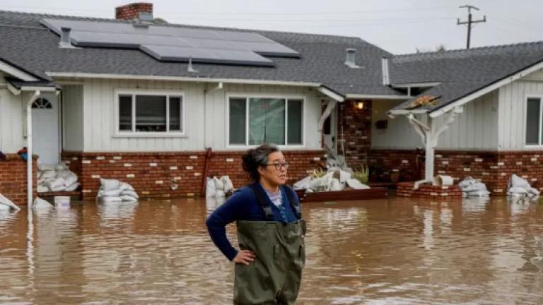 A woman standing in flood waters from huge amounts of rain in front of her home in a neighborhood off of Holohan Road near Watsonville, California, January 9, 2023