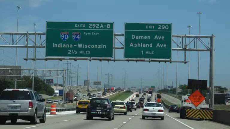 Cars drive on I-55 heading to Chicago, with highway signs announcing exists for Damen Ave and Ashland Ave and for 90/94 expressways.